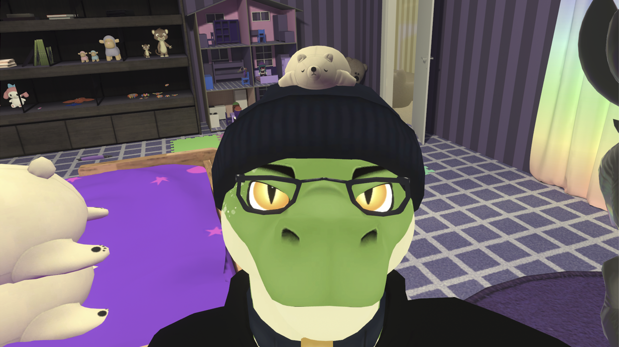 VRChat image of a lizard-like person in glasses, black beanie, choker, and hoodie, looking at the camera. A virtual plush bear has been precariously placed atop their head.
